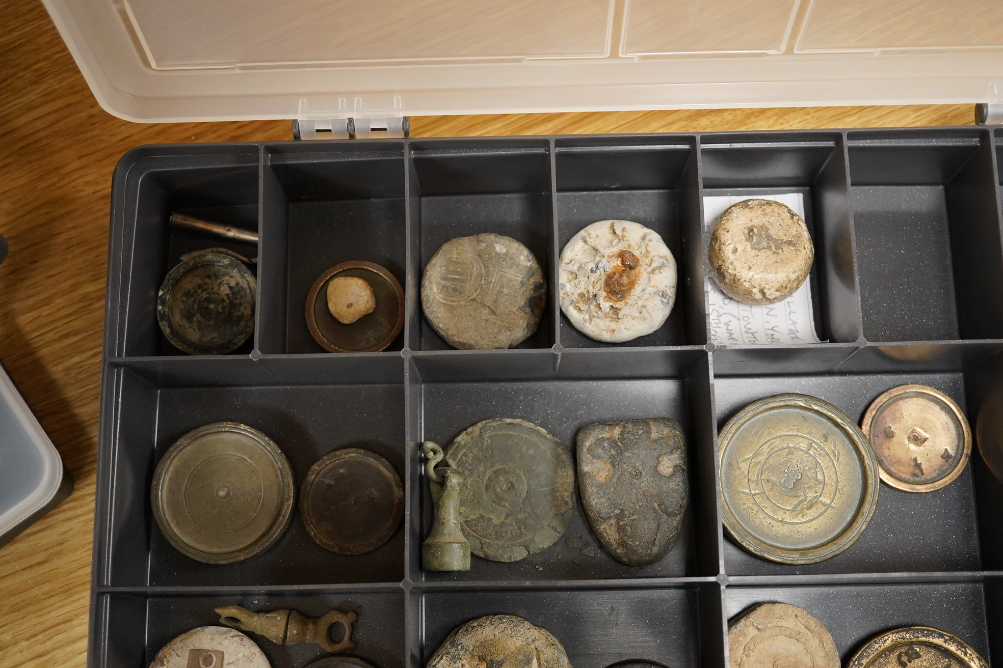A collection of 16th century to 19th century bronze and lead circular trade weights, stamped with Royal Cyphers, weights, proof marks, the assay dagger for London, etc., contained within four plastic collector’s trays